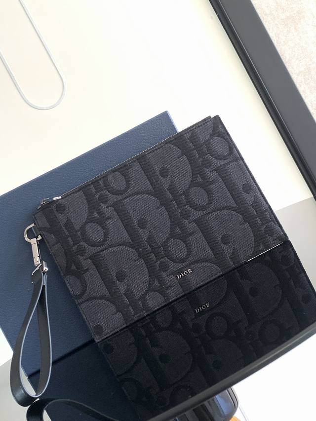 原单 这款 A5 手拿包是一款优雅简约的配饰。采用黑色超大 Oblique 印花面料精心制作，重新演绎品牌经典图案，正面点缀以 Dior 标志，搭配粒面牛皮革饰