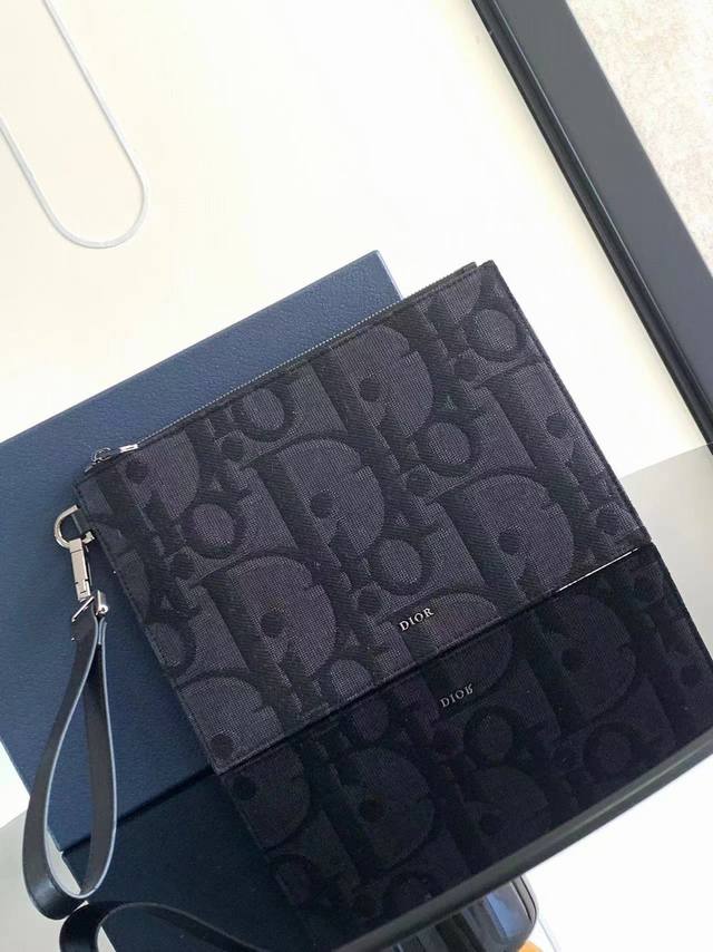 Dior 迪奥这款a5手拿包是一款优雅简约的配饰。采用黑色超大 Oblique 印花面料精心制作，重新演绎品牌经典图案，正面点缀以 Dior 标志，搭配粒面牛皮